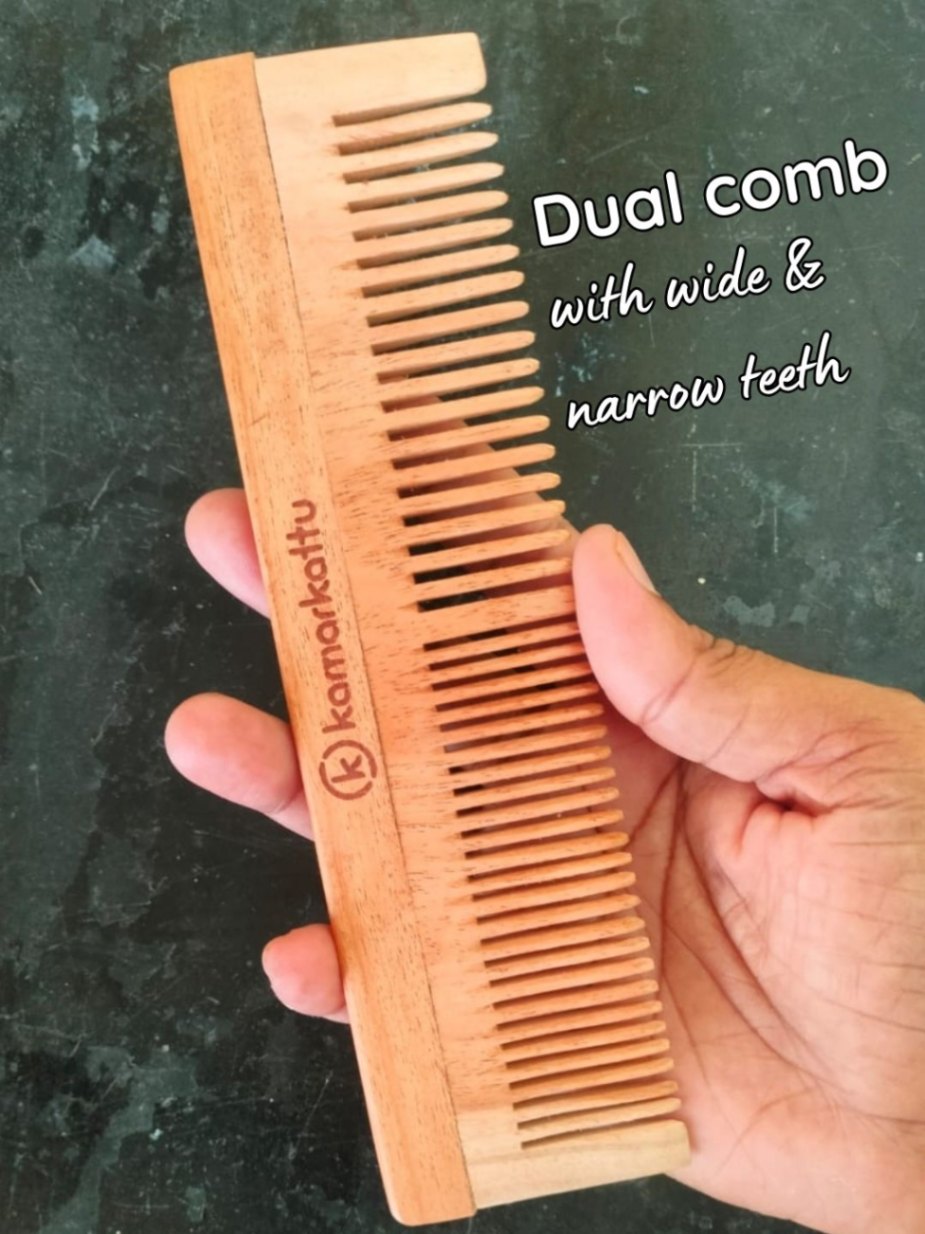 Brown comb with wide and narrow teeth held in a hand against a dark background.