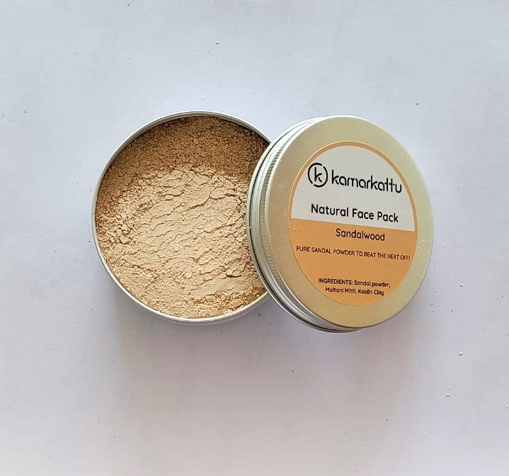 Open round tin of beige face pack powder beside a Kamarkattu Sandalwood labelled lid.