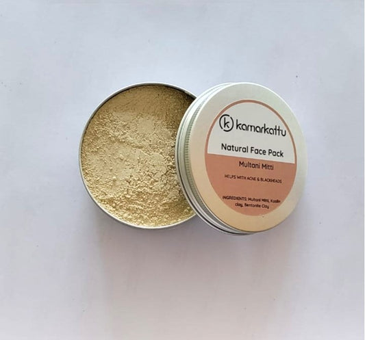 Open round tin of beige Kamarkattu Multani Mitti face pack powder beside its labelled lid.