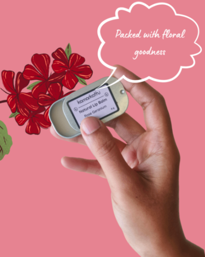 Hand holding a sliding lip balm tin against a pink floral background.