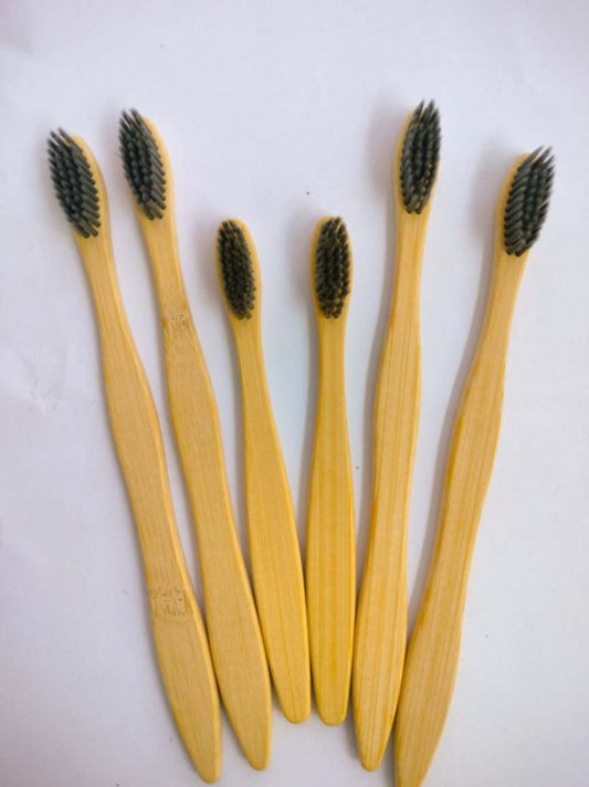 Six brown bamboo toothbrushes with dark bristles arranged on a white background.